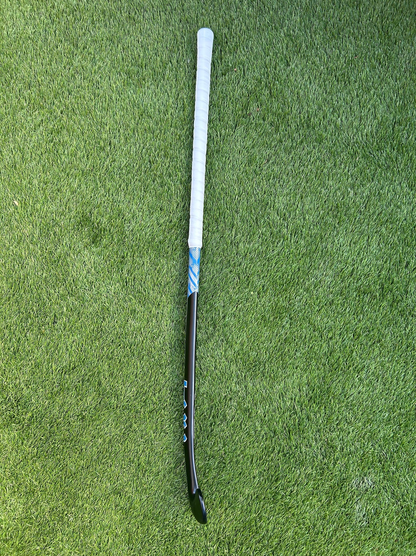 TCC Black Hockey stick on a green grass surface profile view to show bow