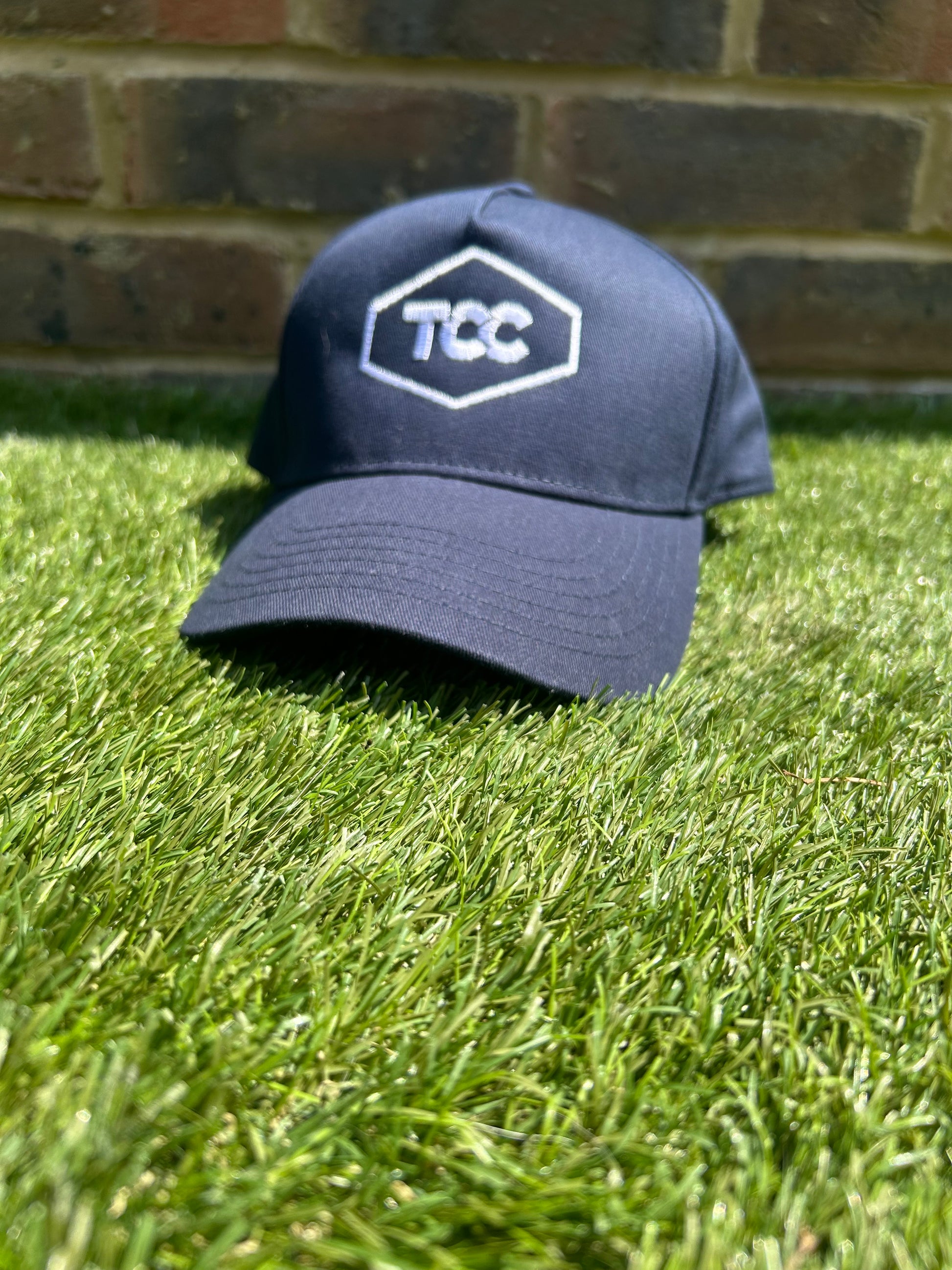 TCC Navy Adjustable Cap front on view positioned on the grass