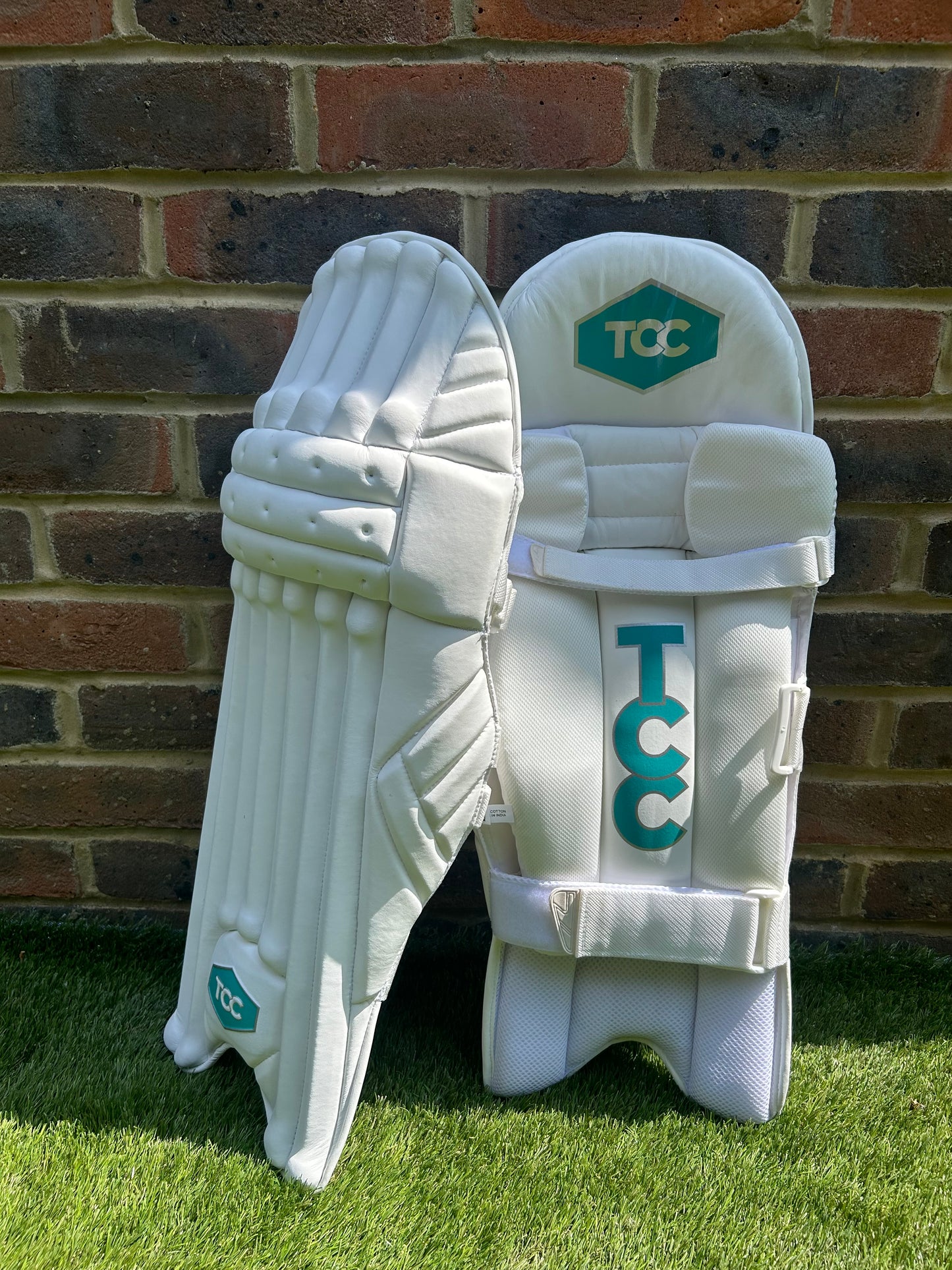 TCC Premium Batting Pads White with Teal Logo and one pad leaning against the other to show the side and inside views