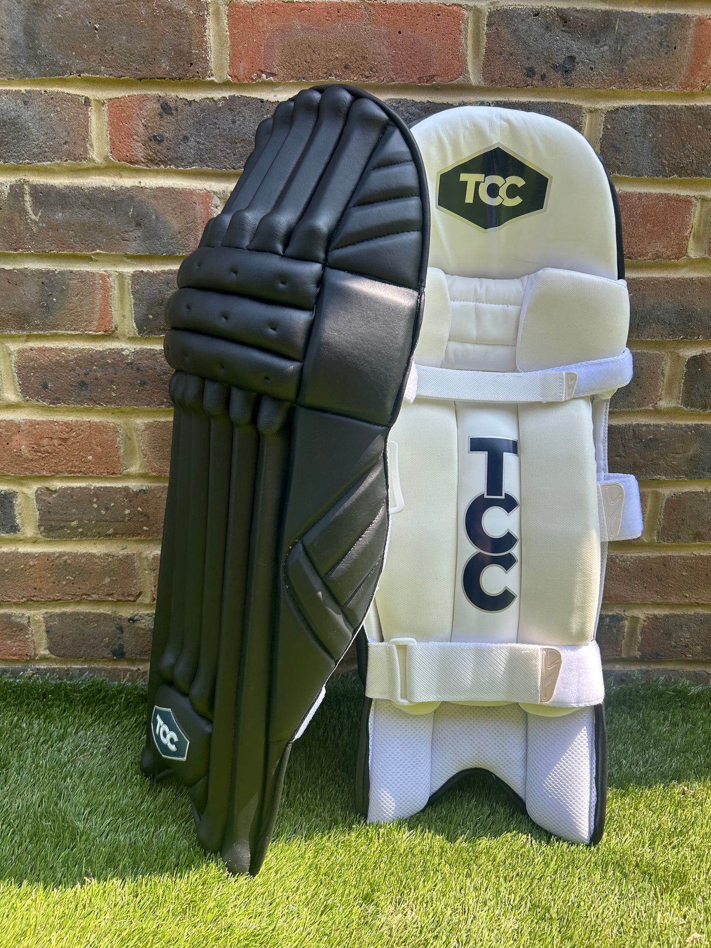 TCC Premium Black Batting Pads with Navy Logo offering a side on view with one pad leaning against the other