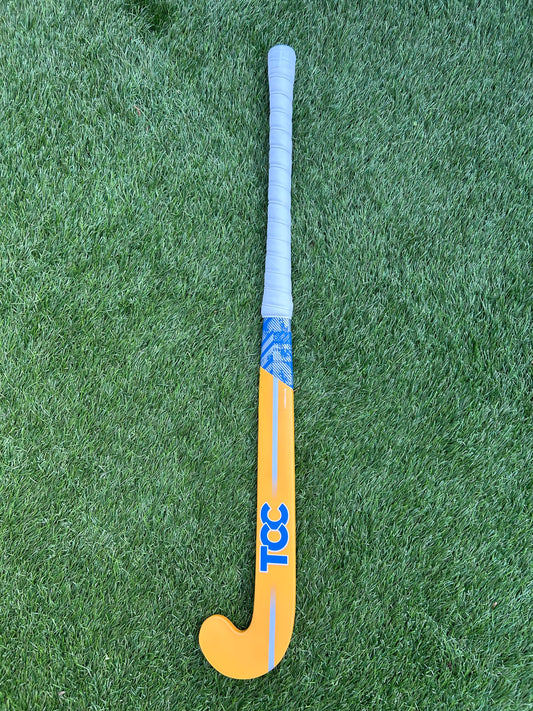 TCC Yellow and Blue Youth Hockey Stick on green grass