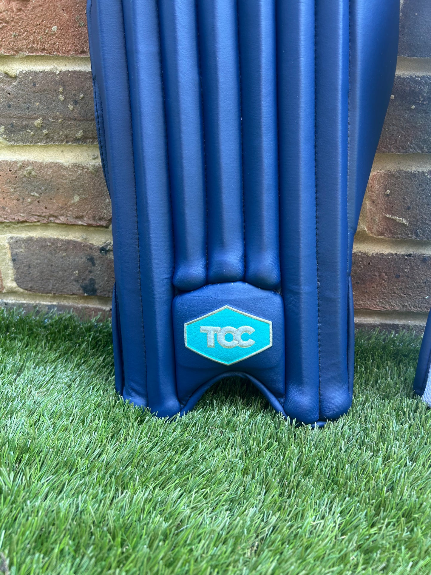 TCC Youth Navy Batting Pads featuring a close up of the Teal and silver hexagon logo