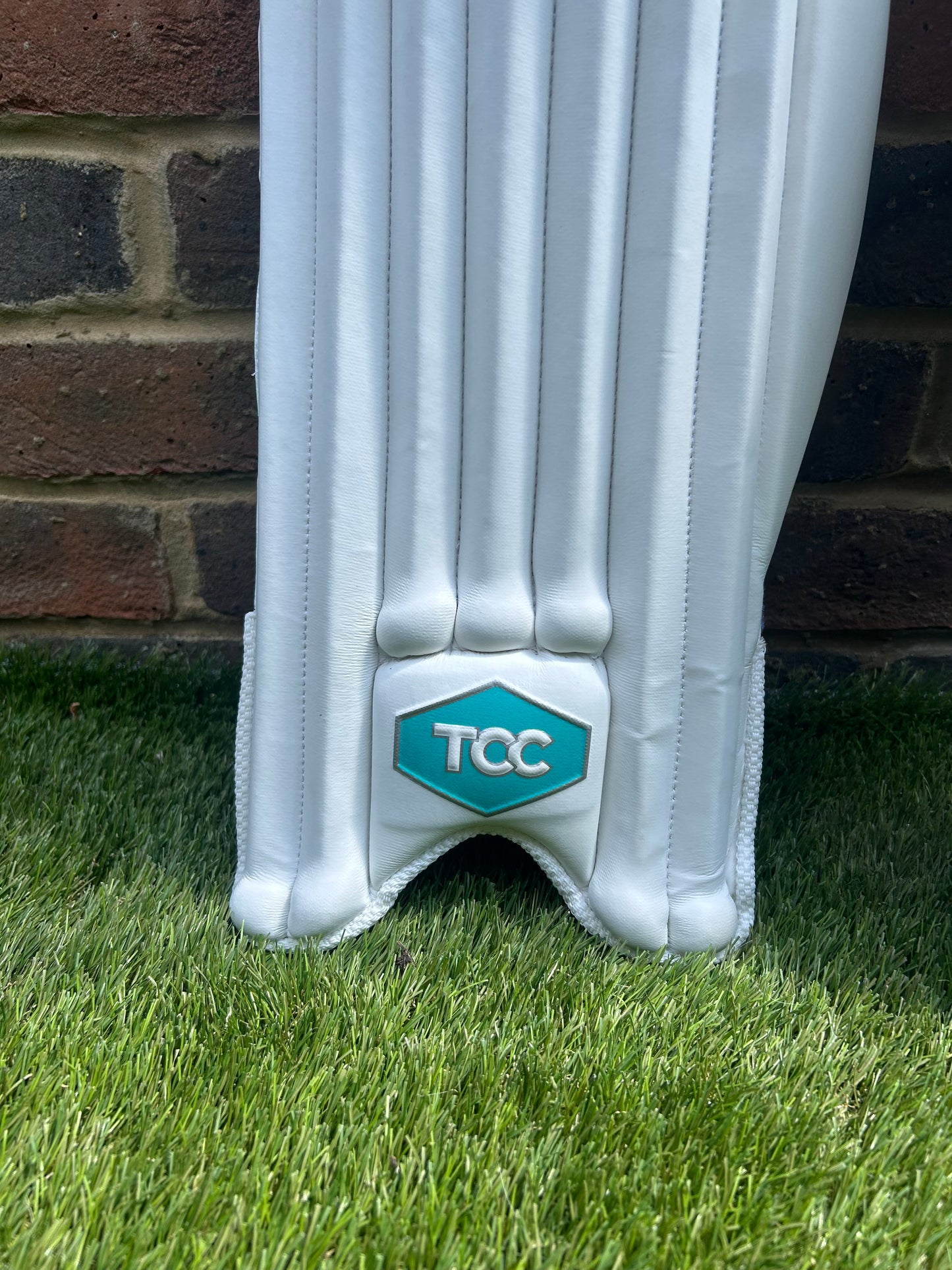 TCC Youth Batting Pads in white feature of Teal Logo on front of batting pads