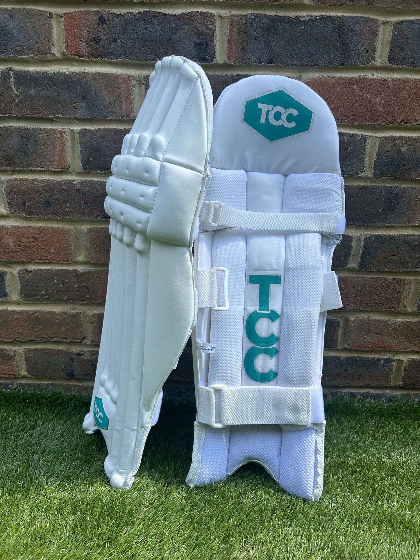 TCC Youth White Batting Pads with Teal Logo with side on and inside leg view featuring the hexagon and vertical versions of TCC logo
