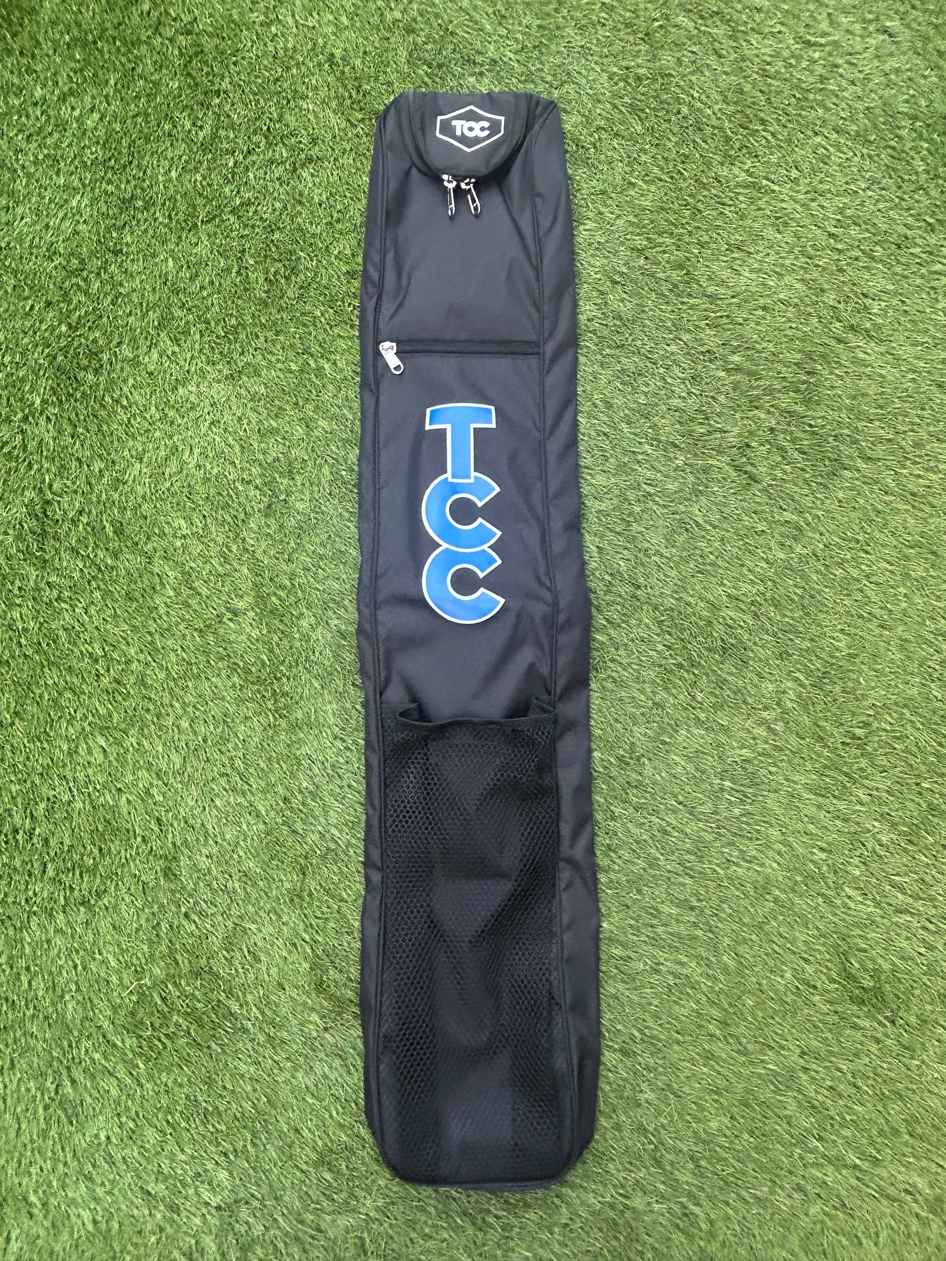 Black TCC Hockey stick bag with blue TCC logo on a green grass background