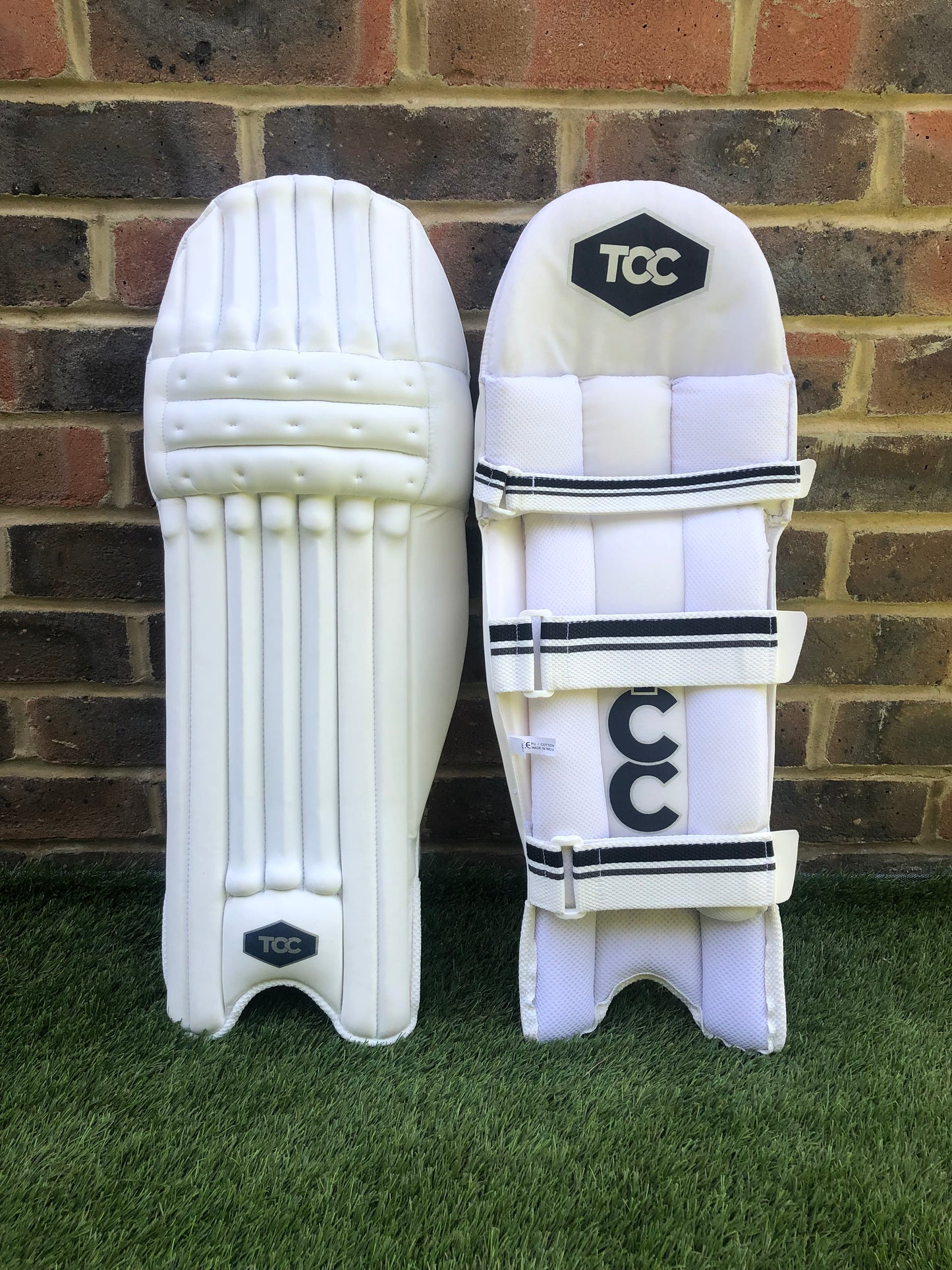 TCC Youth Batting pads front and back view upright against brick wall