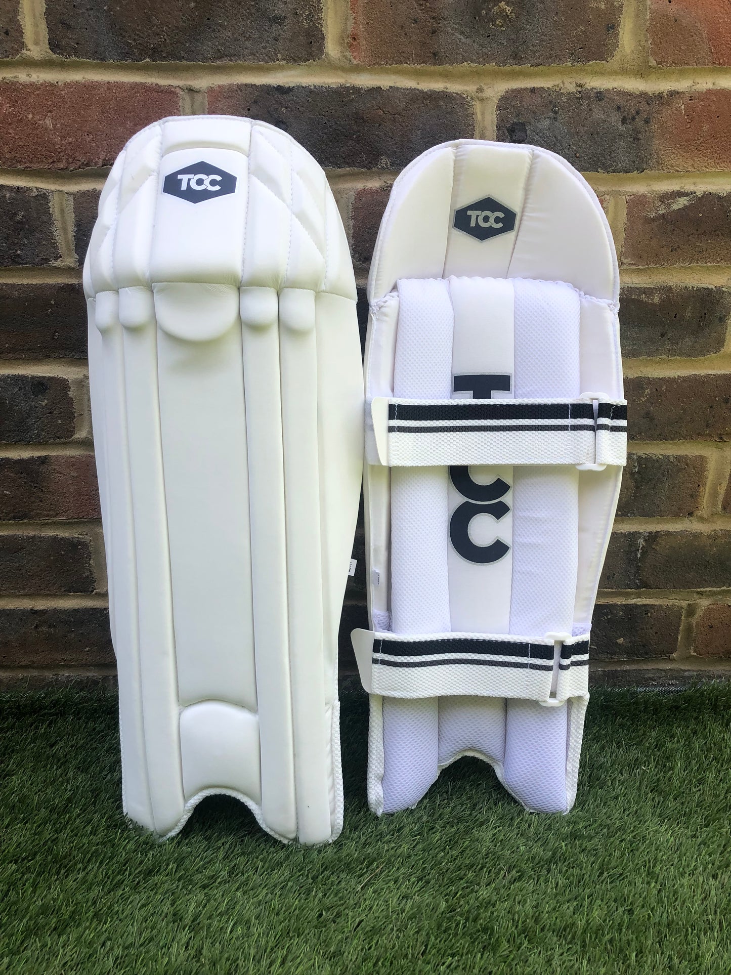 TCC Wicket keeping pads showing front and back view upright against wall