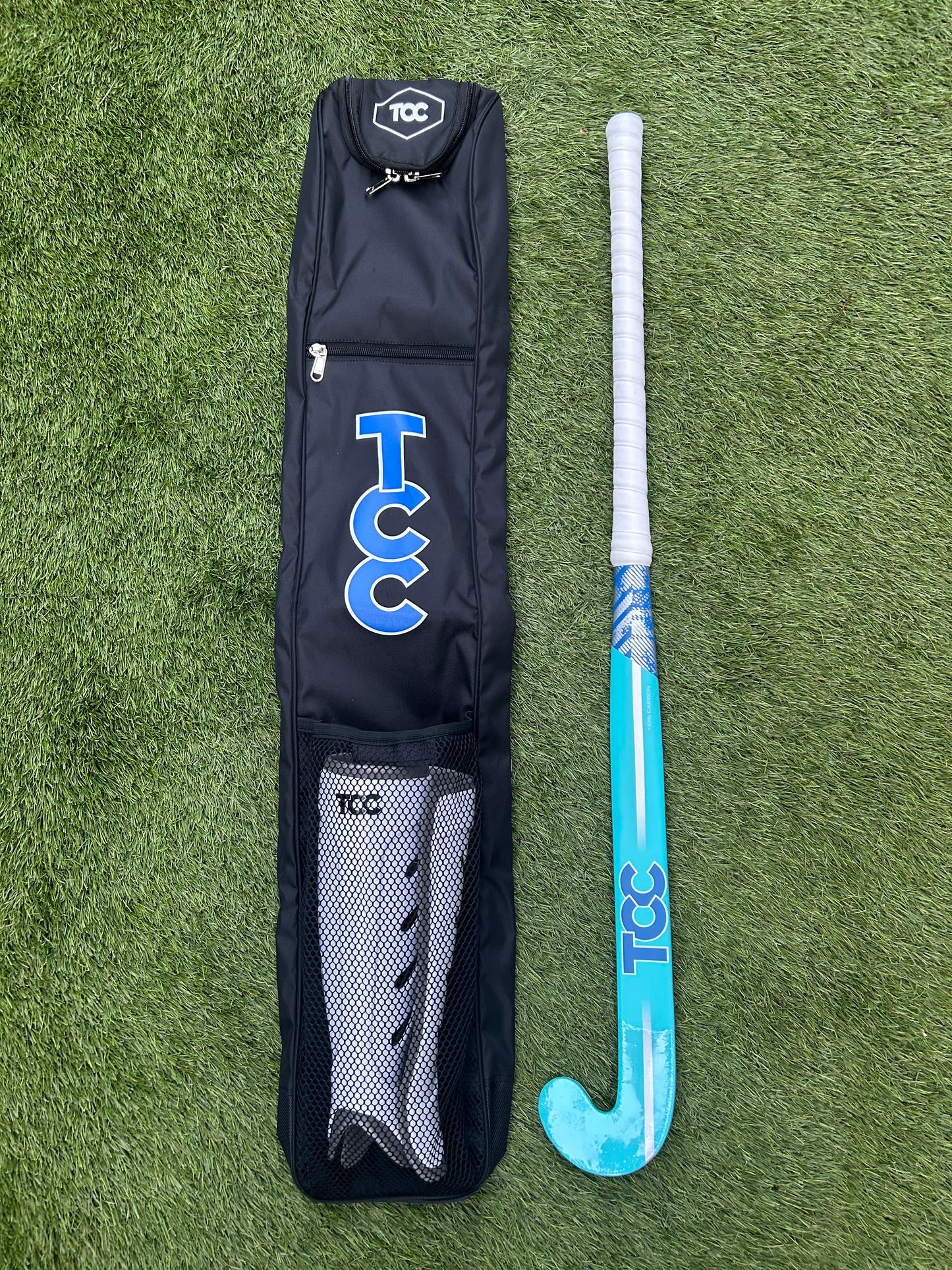 TCC Hockey Stick bag with TCC Pro Shin pads in the mesh pocket and teal and blue stick alongside the bag