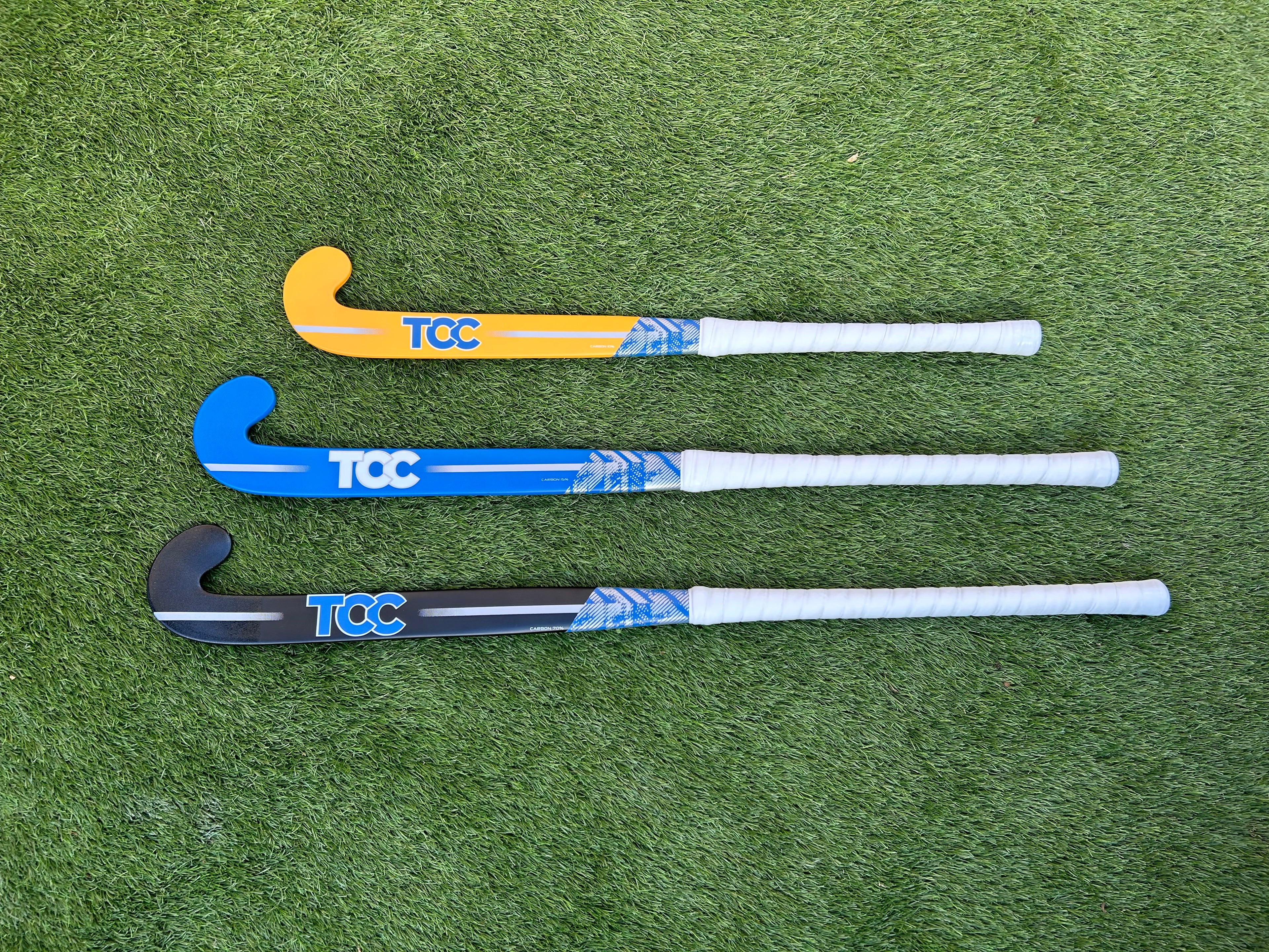 Three hockey sticks with TCC branding on a green field