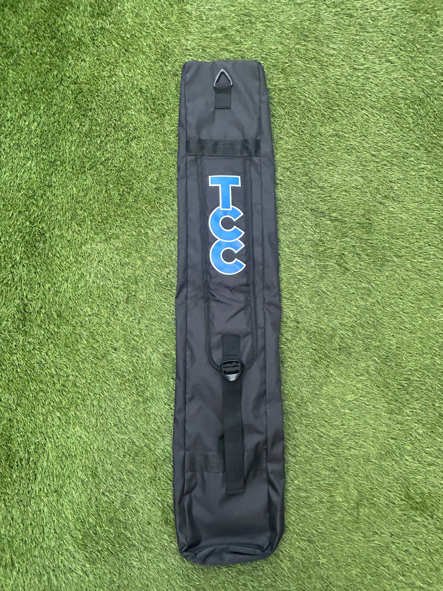 TCC Hockey stick bag reverse view with shoulder strap and TCC logo on the strap laid on grass
