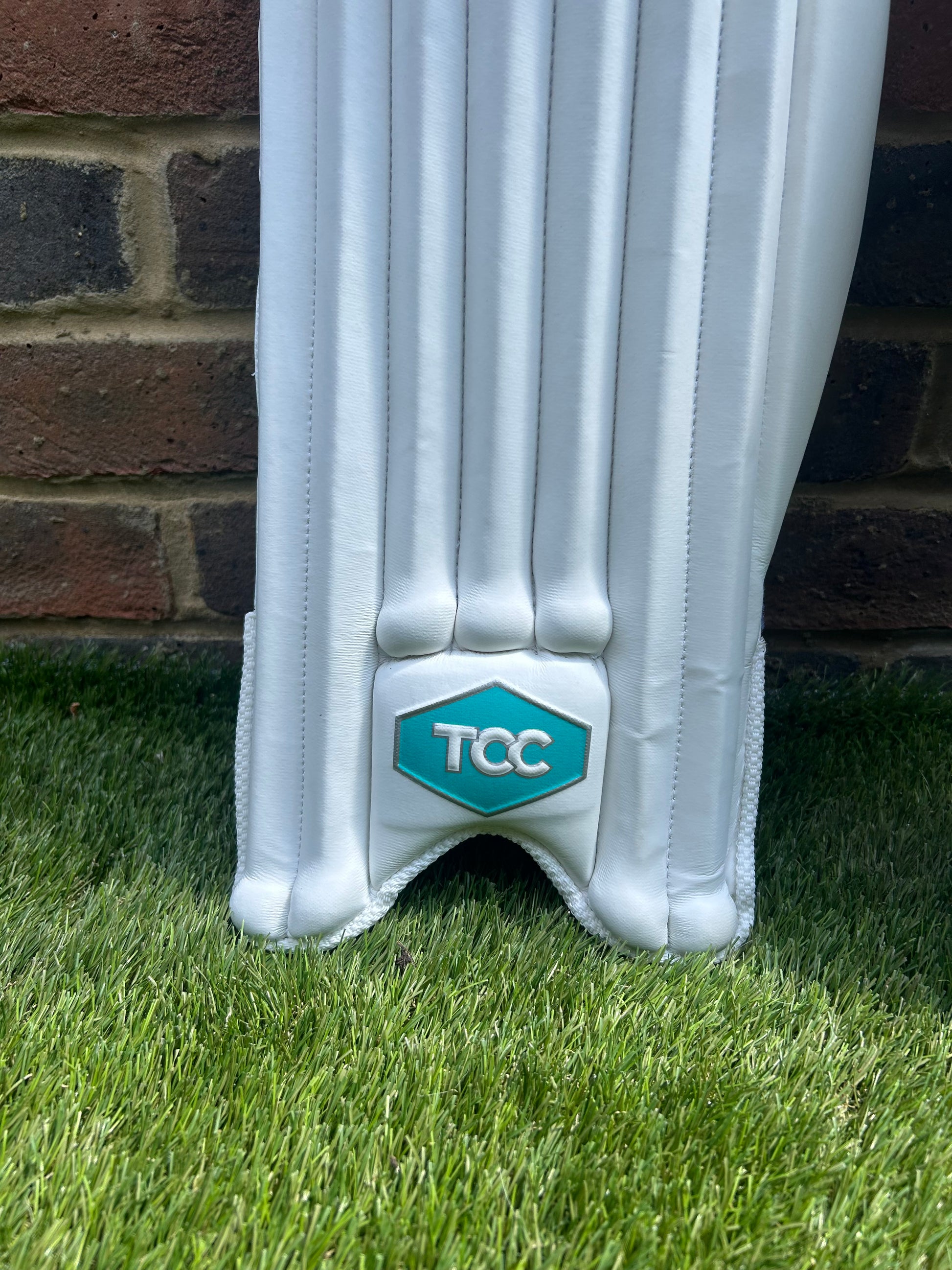 TCC Youth Batting Pads in white feature of Teal Logo on front of batting pads